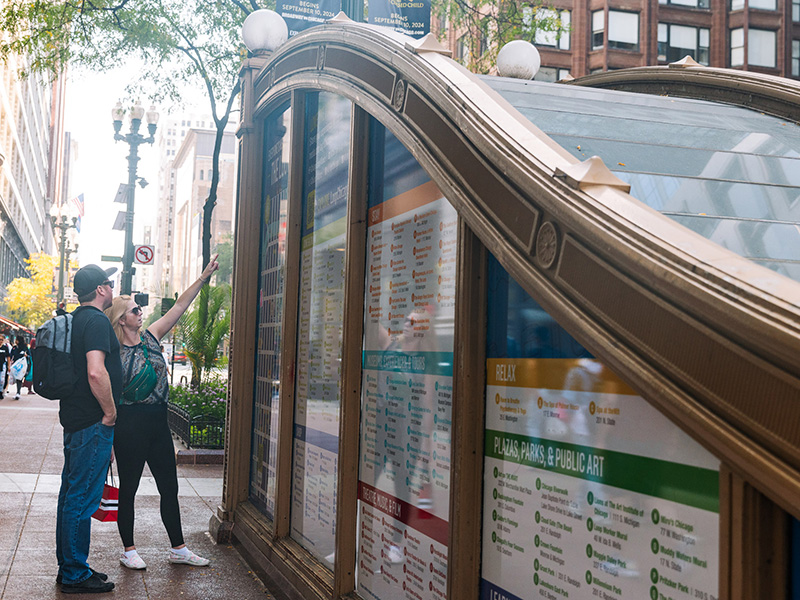 A man and a woman looking at a Chicago Loop Alliance Kiosk on a summer day