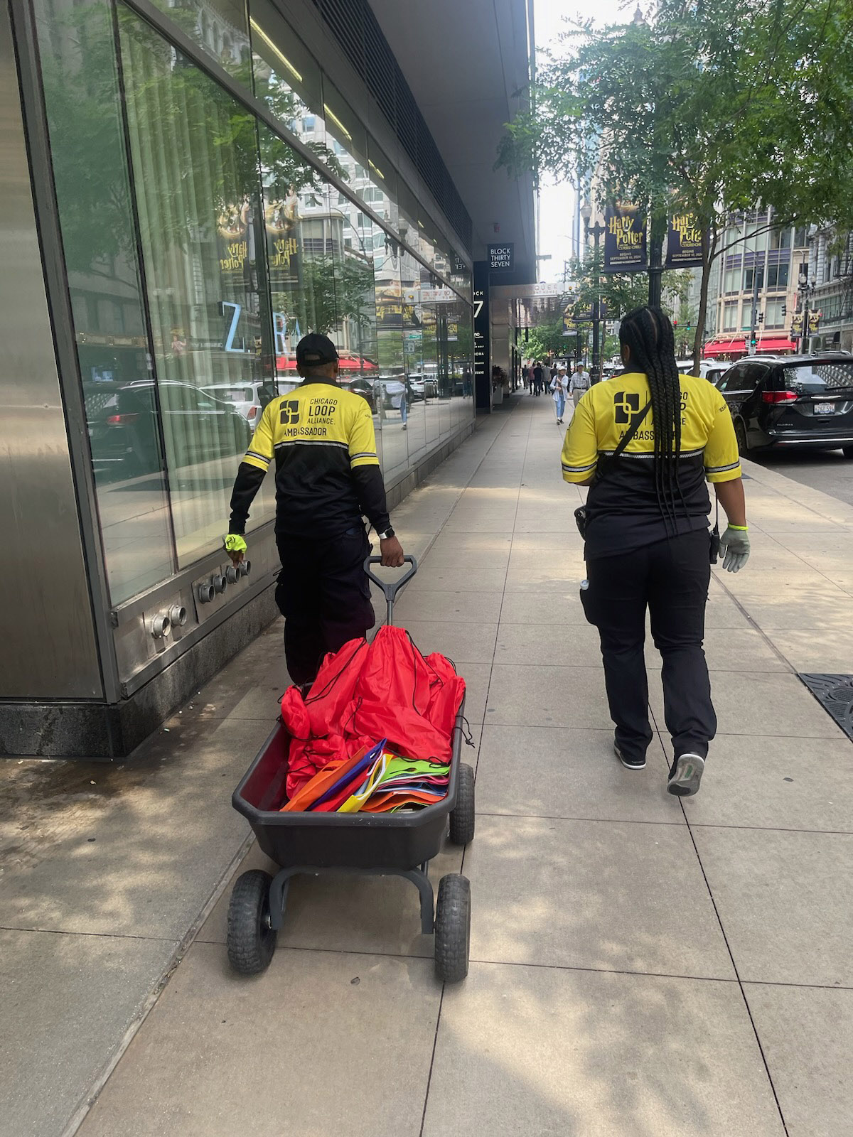 Two Chicago Loop Alliance Street Team Ambassadors walking with a wheelbarrow of supplies